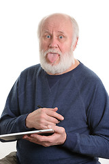 Image showing Funny old man with tongue sticking out using tablet computer isolated on white