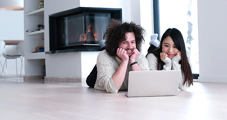 Image showing young multiethnic couple using a laptop on the floor