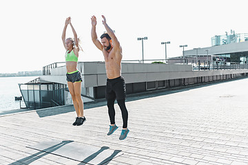 Image showing Fit fitness woman and man doing fitness exercises outdoors at city