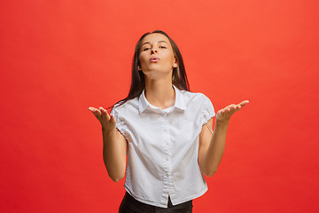 Image showing Beautiful female half-length portrait isolated on red studio backgroud. The young emotional surprised woman