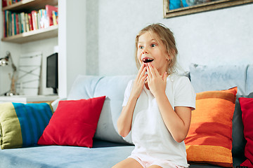 Image showing Little surprised teen girl watching tv at home.