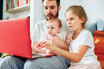 Image showing Proud father holding his baby daughters at home