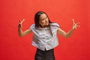 Image showing Portrait of an angry woman looking at camera isolated on a red background