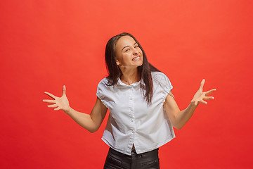 Image showing Beautiful female half-length portrait isolated on red studio backgroud. The young emotional surprised woman