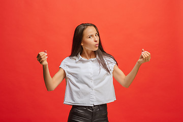 Image showing Portrait of an angry woman looking at camera isolated on a red background