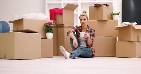 Image showing woman with many cardboard boxes sitting on floor