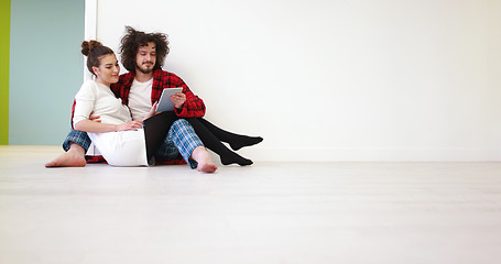 Image showing Young Couple using digital tablet on the floor