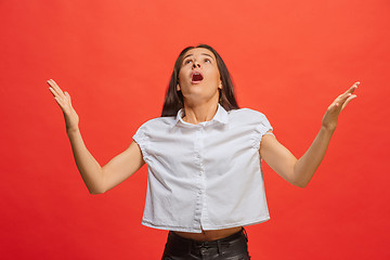 Image showing Beautiful female half-length portrait isolated on red studio backgroud. The young emotional surprised woman