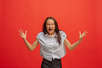 Image showing The young emotional angry woman screaming on red studio background