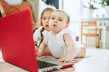 Image showing Portrait of little baby girl looking at camera with a laptop