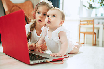 Image showing Portrait of little baby girl looking at camera with a laptop