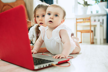 Image showing Portrait of little baby girl looking at camera with a laptop