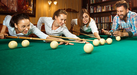 Image showing Young men and women playing billiards at office after work.