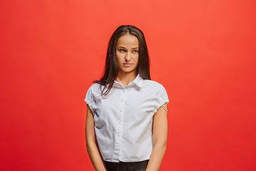 Image showing The serious business woman standing and looking at camera against red background.