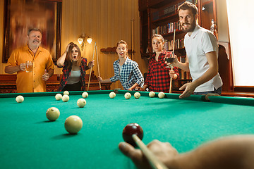 Image showing Young men and women playing billiards at office after work.