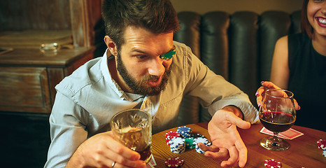 Image showing Side view photo of friends sitting at wooden table. Friends having fun while playing board game.