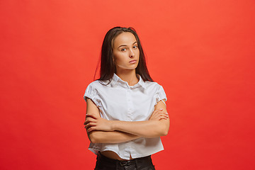 Image showing The serious business woman standing and looking at camera against red background.