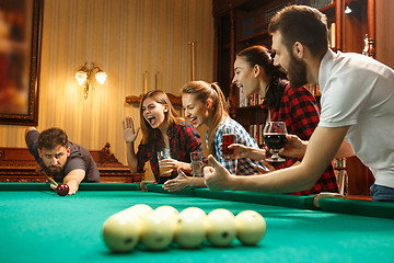 Image showing Young men and women playing billiards at office after work.