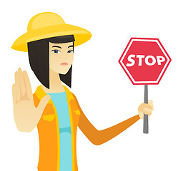 Image showing Young asian farmer holding stop road sign.