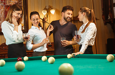 Image showing Young men and women playing billiards at office after work.