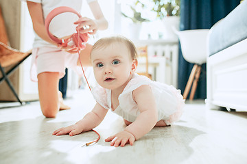 Image showing Cute young baby sitting on the floor at home playing with headphones