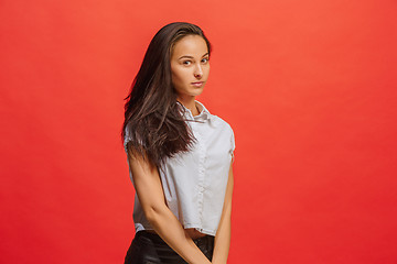 Image showing The serious business woman standing and looking at camera against red background.