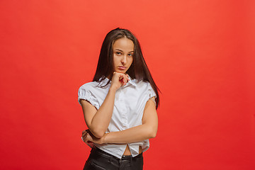 Image showing The serious business woman standing and looking at camera against red background.