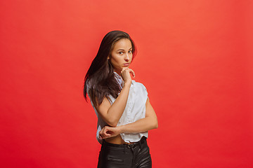 Image showing The serious business woman standing and looking at camera against red background.