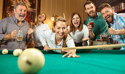 Image showing Young men and women playing billiards at office after work.