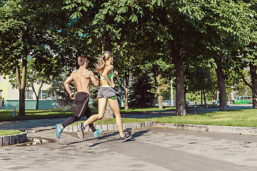 Image showing Pretty sporty woman and man jogging at city