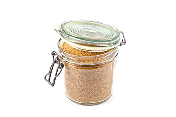 Image showing Brown cane sugar in glass jar isolated on white background.