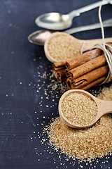 Image showing Brown cane sugar, cinnamon sticks and star anise closeup on blac