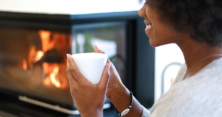 Image showing black woman reading book  in front of fireplace