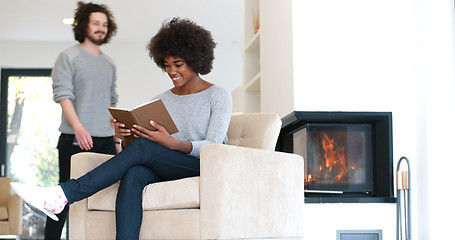 Image showing multiethnic couple hugging in front of fireplace