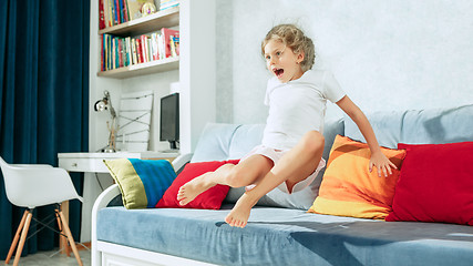 Image showing Little surprised teen girl watching tv at home.