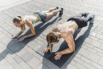 Image showing Fit fitness woman and man doing fitness exercises outdoors at city