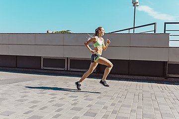 Image showing Pretty sporty woman jogging at city