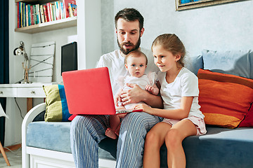 Image showing Proud father holding his baby daughters at home