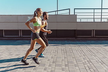 Image showing Pretty sporty woman and man jogging at city