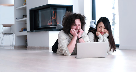 Image showing young multiethnic couple using a laptop on the floor