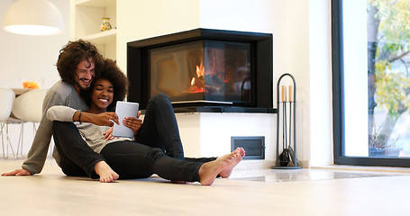 Image showing multiethnic couple using tablet computer on the floor