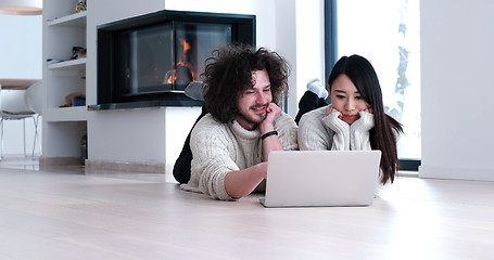 Image showing young multiethnic couple using a laptop on the floor