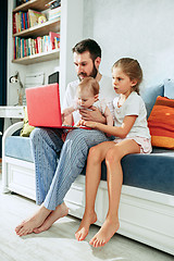 Image showing Proud father holding his baby daughters at home