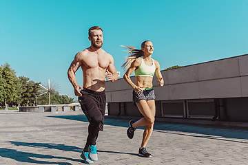 Image showing Pretty sporty woman and man jogging at city