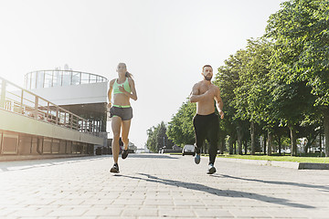 Image showing Pretty sporty woman and man jogging at city