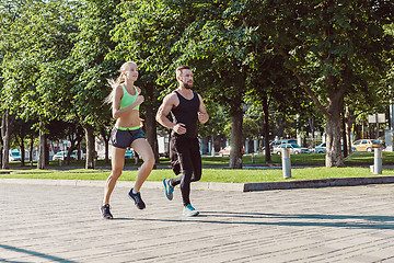 Image showing Pretty sporty woman and man jogging at city