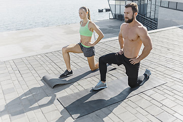 Image showing Fit fitness woman and man doing fitness exercises outdoors at city