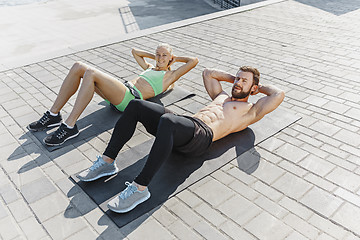 Image showing Fit fitness woman and man doing fitness exercises outdoors at city