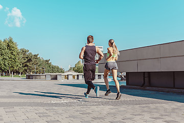 Image showing Pretty sporty woman and man jogging at city