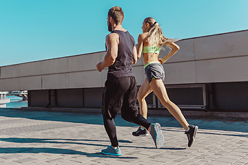 Image showing Pretty sporty woman and man jogging at city